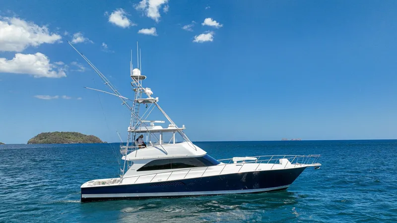 The Image of Side Profile on Open Water The 2005 Viking 61 Convertible 'Honey Girl' is showcased cruising on open waters. Its sleek hull design and robust sportfishing tower stand out against a clear blue sky. This vessel combines luxury with performance, ideal for serious anglers and leisure c - 6449505