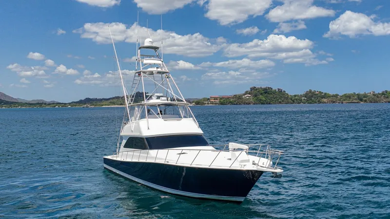 Slide: The Image of Bow View with Tuna Tower This striking image showcases the sleek bow of the 2005 Viking 61 Convertible, Honey Girl, cruising gracefully on open water. The vessel features a distinctive navy-blue hull contrasted by a white superstructure, enhancing its elegant profile. Prominent i - 6449584