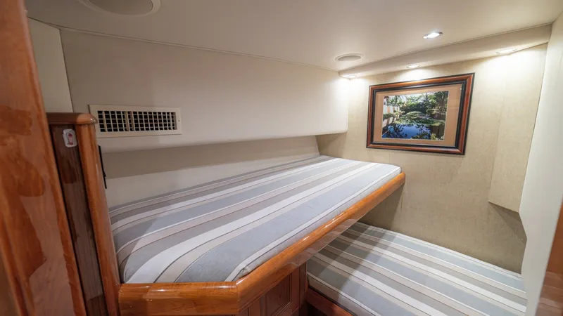 Slide: The Image of Cozy Twin Bunk Stateroom This inviting stateroom features twin bunk beds adorned with striped bedding, offering comfort and style for guests. Warm wood accents complement the neutral walls, while recessed lighting creates a soothing ambiance. A framed artwork adds a personal touc - 6449523