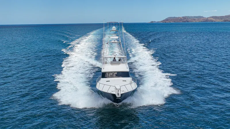 Slide: The Image of Aerial View of Yacht Underway The 2005 Viking 61 Convertible 'Honey Girl' is captured in full stride, demonstrating its powerful performance and sleek design. The aerial perspective highlights the vessel's expansive flybridge and distinct bow shape slicing through the water. The surro - 6449605