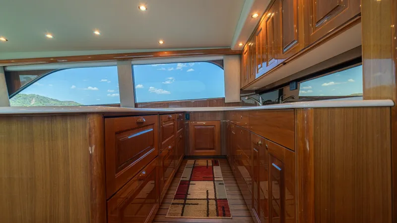 Slide: The Image of Galley with Rich Wood Cabinetry The galley of the 2005 Viking 61 Convertible 'Honey Girl' showcases exquisite craftsmanship with its rich wood cabinetry and polished finishes. Ample storage space is complemented by a sleek countertop, while large windows provide natural light and stunni - 6449513