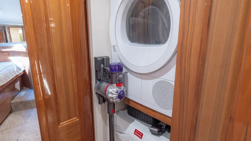 Slide: The Image of Laundry Closet with Washer/Dryer Combo This efficient laundry closet on the Viking 61 Convertible 'Honey Girl' features a stacked washer/dryer combo, perfect for extended voyages. The compact design maximizes space while providing essential amenities for onboard convenience. The warm wooden ca - 6449531