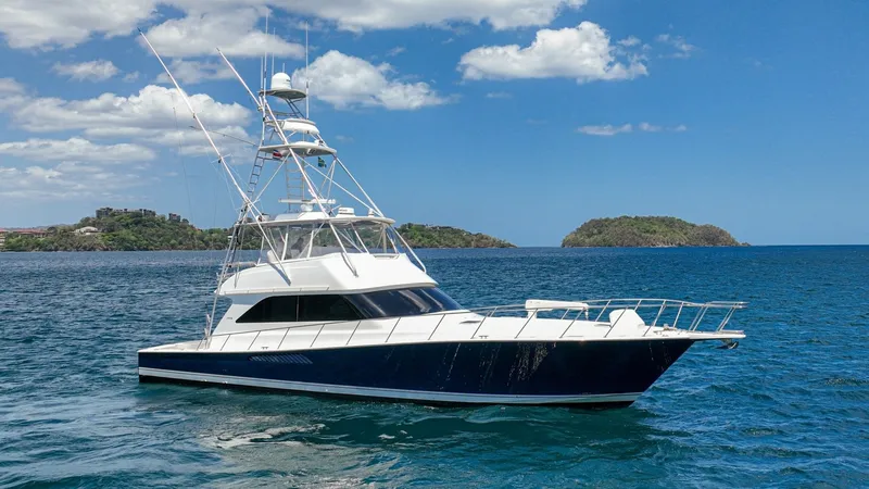 Slide: The Image of Starboard Profile of Viking 61 Convertible This image showcases the elegant starboard profile of the 2005 Viking 61 Convertible, 'Honey Girl.' The yacht's sleek lines are complemented by a deep blue hull, offering a classic and sophisticated appearance. The spacious flybridge and robust tower stru - 6449583