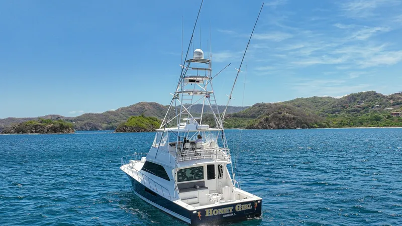 Slide: The Image of Aft Deck and Tuna Tower View This image showcases the sleek aft deck of the 2005 Viking 61 Convertible, 'Honey Girl.' The spacious deck is ideal for fishing and entertaining, complemented by the towering tuna tower, which provides excellent visibility and navigation support. The vess - 6449590