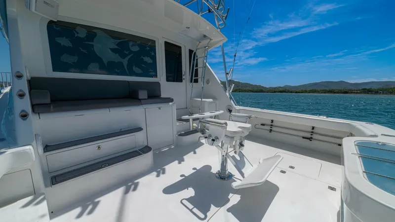 Slide: The Image of Spacious Aft Deck with Fishing Chair The aft deck of the 2005 Viking 61 Convertible 'Honey Girl' offers a spacious and functional area, perfect for fishing enthusiasts. It features a centrally positioned fishing chair and built-in bench seating, providing comfort and convenience. The deck's - 6449558