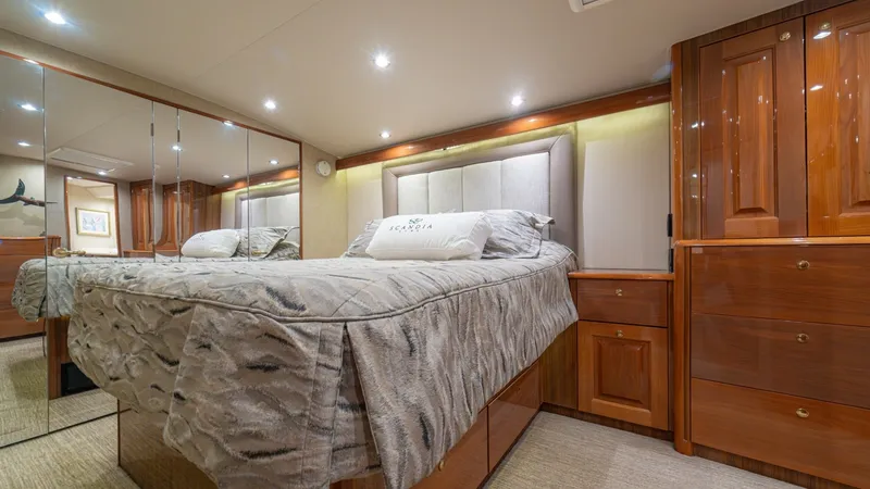Slide: The Image of Master Stateroom with Mirrored Closets The master stateroom on the 2005 Viking 61 Convertible 'Honey Girl' features a plush, queen-sized bed framed by elegant wood cabinetry and mirrored closets that enhance the sense of space. Ambient recessed lighting creates a warm, inviting atmosphere, whi - 6449533