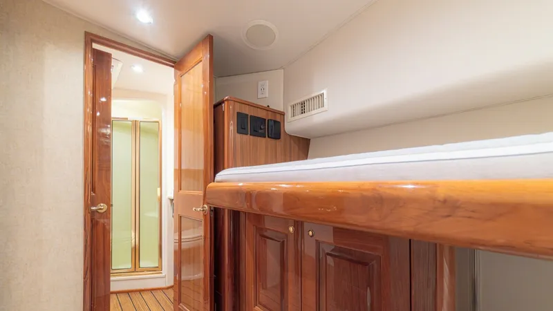 Slide: The Image of Guest Cabin with En-Suite Access This inviting guest cabin features a polished wooden bunk with ample storage beneath, showcasing the craftsmanship of the Viking 61 Convertible. The warm wood finishes create a cozy ambiance, while the direct access to a private en-suite bathroom with a g - 6449526