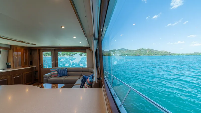 Slide: The Image of Salon with Panoramic Ocean View The salon of the 2005 Viking 61 Convertible offers a spacious and inviting area with plush seating and elegant wood finishes. Large panoramic windows provide breathtaking views of the ocean, enhancing the sense of openness and light. The modern lighting a - 6449517