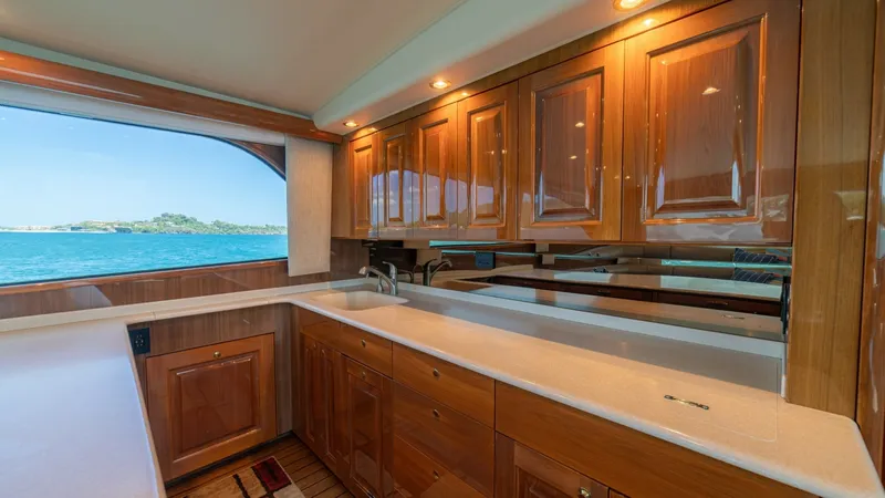 Slide: The Image of Galley with Ocean View Window This well-appointed galley on the 2005 Viking 61 Convertible features high-gloss wooden cabinetry and pristine countertops, offering ample storage and workspace. Large windows provide stunning ocean views, enhancing the open and inviting atmosphere. Reces - 6449514