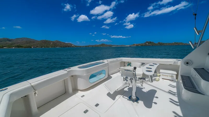 Slide: The Image of Spacious Aft Deck with Fishing Chair The aft deck of the 2005 Viking 61 Convertible, 'Honey Girl', offers a spacious area perfect for fishing enthusiasts. It features a robust, centrally mounted fighting chair, ideal for reeling in the big catch. The clean, white deck provides ample space fo - 6449559