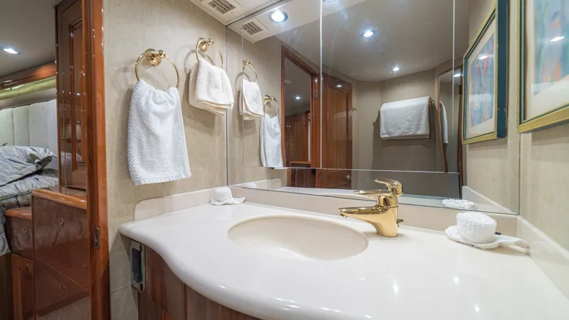 Slide: The Image of Luxurious Ensuite Bathroom This elegant ensuite bathroom on the 2005 Viking 61 Convertible features a sleek, curved countertop with a stylish gold faucet. The space is enhanced by large mirrors, providing a sense of openness, and is well-lit by recessed lighting. Thoughtfully desig - 6449541