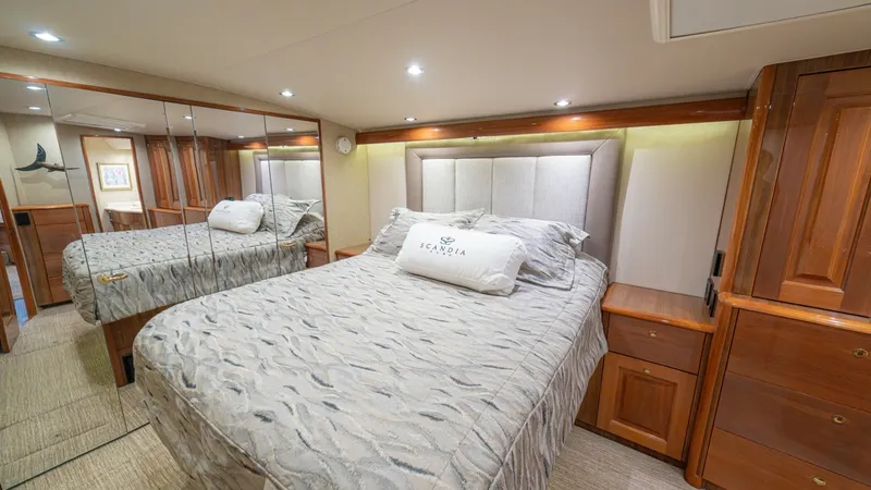 Slide: The Image of Luxurious Master Stateroom Interior This elegant master stateroom on the 2005 Viking 61 Convertible 'Honey Girl' features a plush queen-sized bed with a stylish upholstered headboard, creating a cozy and inviting atmosphere. The room is enhanced by warm wood cabinetry and mirrored closets, - 6449508