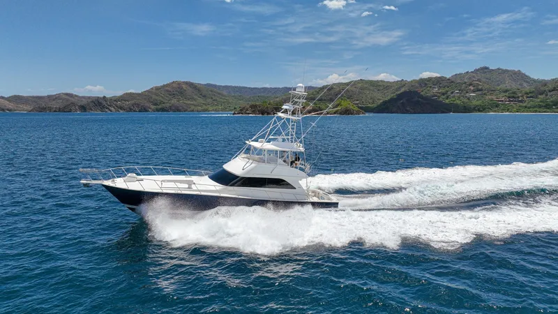Slide: The Image of Viking 61 Convertible at Sea The 2005 Viking 61 Convertible, known as 'Honey Girl,' is captured cruising swiftly across the open sea. This dynamic side view showcases its sleek, aerodynamic hull and robust flybridge equipped with a tower. With a powerful wake trailing behind, the ves - 6449598
