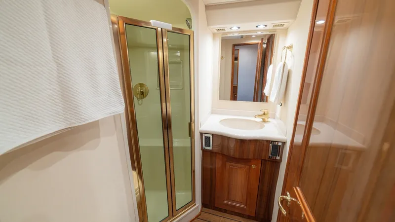Slide: The Image of Elegant Ensuite Bathroom with Shower This stylish ensuite bathroom features a glass-enclosed shower with brass fixtures, complementing the warm wood cabinetry. A sleek countertop with an integrated sink provides ample space, while recessed lighting adds a touch of elegance. The inviting desi - 6449528
