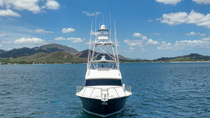 Slide: The Image of Bow View with Tower and Sky This striking bow view of the 2005 Viking 61 Convertible, 'Honey Girl,' showcases its sleek design and powerful presence on the water. The towering flybridge offers an elevated perspective, ideal for navigation and spotting. The hull's deep blue contrasts - 6449585
