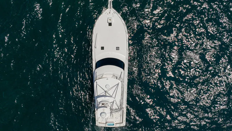 Slide: The Image of Aerial View of Deck and Flybridge This aerial shot captures the sleek design of the 2005 Viking 61 Convertible from above, showcasing its expansive flybridge and clean deck layout. The vessel's streamlined silhouette is highlighted against the sparkling ocean, emphasizing its elegance and - 6449608