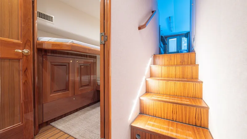 Slide: The Image of Lower Deck Stairway and Cabin Entry This image showcases the elegant stairway leading to the lower deck of the 2005 Viking 61 Convertible. The warm, glossy wood finish on the steps complements the sleek cabin entryway, creating a welcoming and luxurious ambiance. Soft lighting enhances the - 6449522