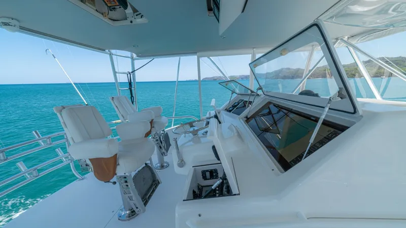 Slide: The Image of Flybridge Helm Station The flybridge helm station of the 2005 Viking 61 Convertible offers a commanding view of the surroundings, accentuated by expansive windows and open-air design. Featuring dual captain's chairs with robust armrests, the helm is equipped with state-of-the-a - 6449566