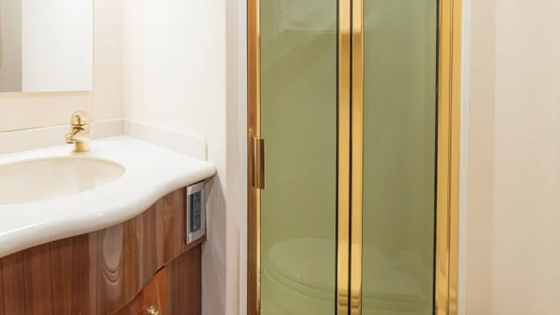 Slide: The Image of Elegant En-Suite Bathroom This en-suite bathroom on the 2005 Viking 61 Convertible 'Honey Girl' features a sophisticated design with a sleek, curved vanity and gold-toned fixtures. The glass-enclosed shower provides a modern touch, complementing the warm wood cabinetry. The space - 6449548
