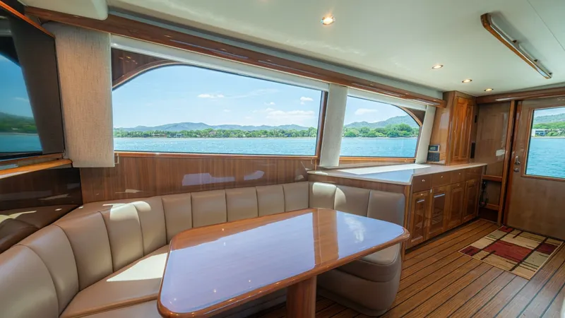 Slide: The Image of Salon with Panoramic Windows The salon of the 2005 Viking 61 Convertible 'Honey Girl' offers a spacious and inviting area with expansive panoramic windows that provide stunning views. The plush, U-shaped seating is complemented by a polished wooden table, creating a perfect space for - 6449520