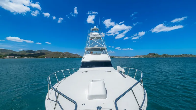 Slide: The Image of Bow View with Tower This image showcases the sleek bow of the 2005 Viking 61 Convertible, 'Honey Girl', against a stunning seascape. The spacious foredeck is equipped with sturdy railings, providing safety and comfort for passengers. Above, the towering flybridge offers exce - 6449579