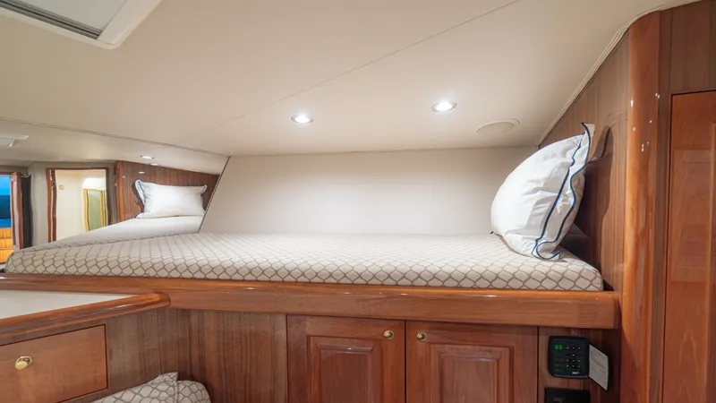 Slide: The Image of Guest Cabin Upper Bunk The guest cabin features a cozy upper bunk with elegant wood finishes and soft, ambient lighting. The space is thoughtfully designed for comfort, with plush bedding and ample headroom. Below, storage cabinets offer practical space for personal belongings, - 6449546