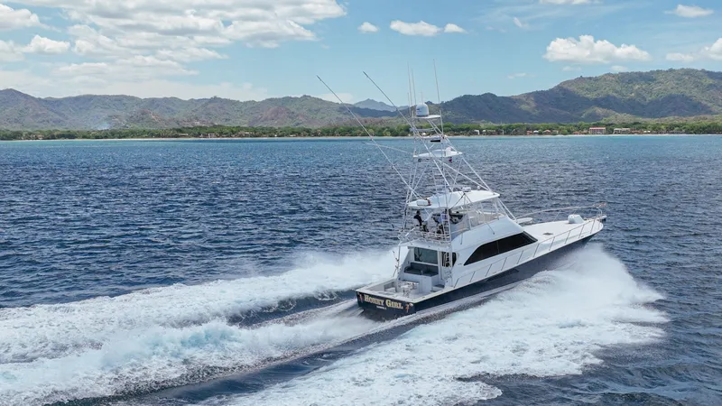 Slide: The Image of Aerial View of Viking 61 in Motion The 2005 Viking 61 Convertible, 'Honey Girl,' cuts through the water with impressive speed and agility. The sleek design and powerful engines create a striking wake, showcasing the vessel's performance capabilities. The flybridge and outriggers highlight - 6449602
