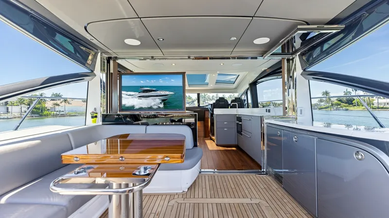Slide: The Image of Spacious Cockpit Forward View The main deck salon of the 2026 PRINCESS V55 offers an elegant and open layout, featuring sleek, modern finishes. Luxurious seating surrounds a polished wooden table, perfect for social gatherings. Expansive windows and a retractable roof panel provide ab - 6312323