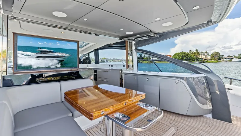 Slide: The Image of Spacious Cockpit Seating with Entertainment System The 2026 PRINCESS V55 features a luxurious cockpit area equipped with a sleek entertainment system, perfect for outdoor gatherings. The elegant teak table is surrounded by plush seating, offering comfort and style. Overhead, the modern design of the canop - 6312334