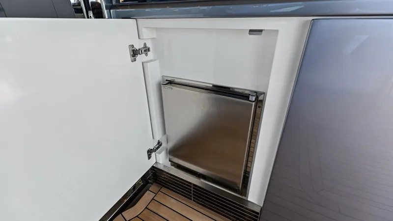 Slide: The Image of Cockpit Icemaker This image showcases the cockpit galley icemaker on the 2026 PRINCESS V55. The sleek, stainless-steel finish of the icemaker complements the modern design of the yacht. The surrounding cabinetry provides seamless integration, enhancing both functionality - 6312337
