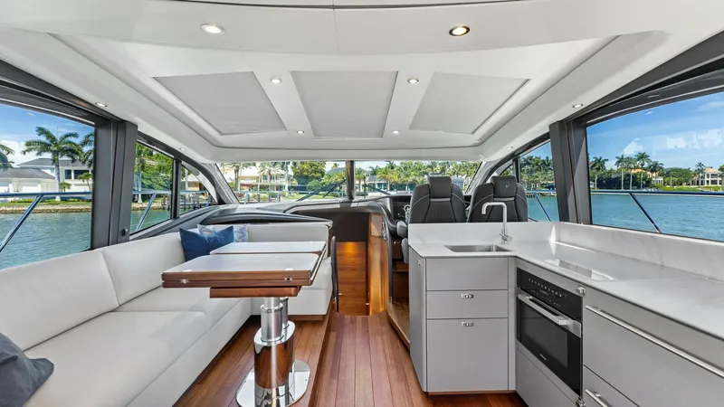 Slide: The Image of Main Salon with Open Galley The 2026 PRINCESS V55's main salon offers an elegant and spacious layout, featuring a sleek open galley with modern appliances and ample counter space. Luxurious seating lines the starboard side, complemented by panoramic windows that flood the space with - 6312338