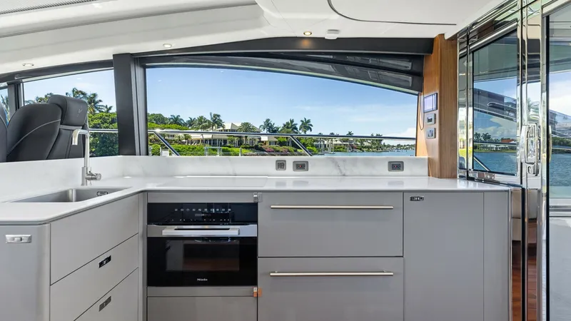 Slide: The Image of Modern Galley with Scenic Views The galley of the 2026 PRINCESS V55 offers a sleek and modern design, featuring high-end appliances and ample storage. Its large windows provide stunning panoramic views, enhancing the open and airy feel. The seamless integration with the salon makes it p - 6312339