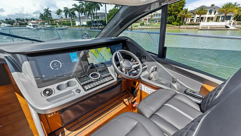 Slide: The Image of Helm Station with Modern Instrumentation The helm station of the 2026 PRINCESS V55 showcases a sleek, modern design with state-of-the-art instrumentation. It features a large, multifunctional display for navigation and controls, set within a sophisticated dashboard. The luxurious captain's seat - 6312342