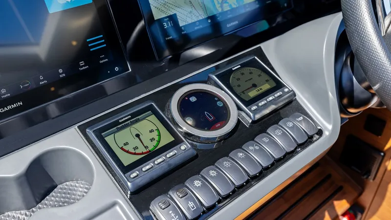 Slide: The Image of Helm Control Console The helm of the 2026 PRINCESS V55 features an advanced control console with state-of-the-art navigation displays and instrumentation. The sleek design integrates digital readouts and tactile controls, providing the operator with intuitive access to all es - 6312343