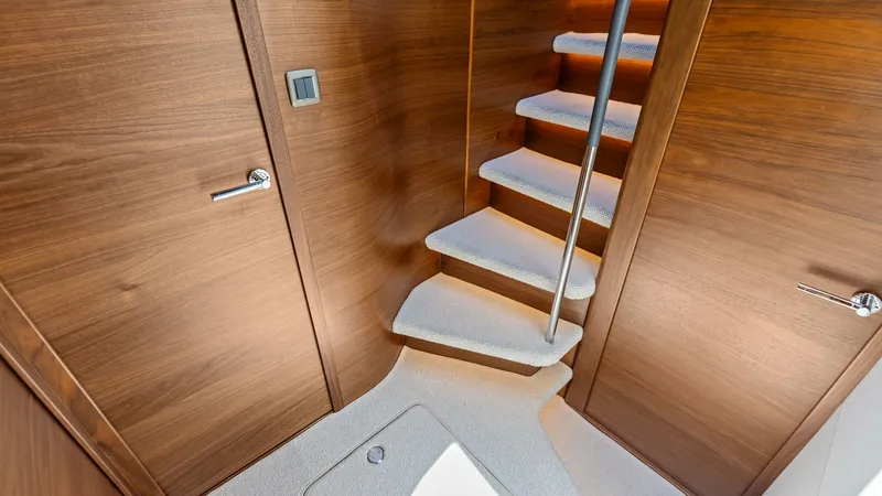Slide: The Image of Companionway and Hallway Entryway The elegant companionway and hallway entryway of the 2026 PRINCESS V55. The sleek wooden paneling and soft, plush carpeting create a warm and inviting atmosphere. The companionway is accented with subtle lighting, enhancing the modern design and providing - 6312346