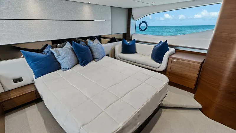 Slide: The Image of Master Stateroom with Ocean View The master stateroom of the 2026 PRINCESS V55 exudes luxury with its spacious layout and elegant design. A large bed adorned with plush pillows is complemented by a sleek sofa, offering ample comfort. The expansive window provides a breathtaking ocean vie - 6312347