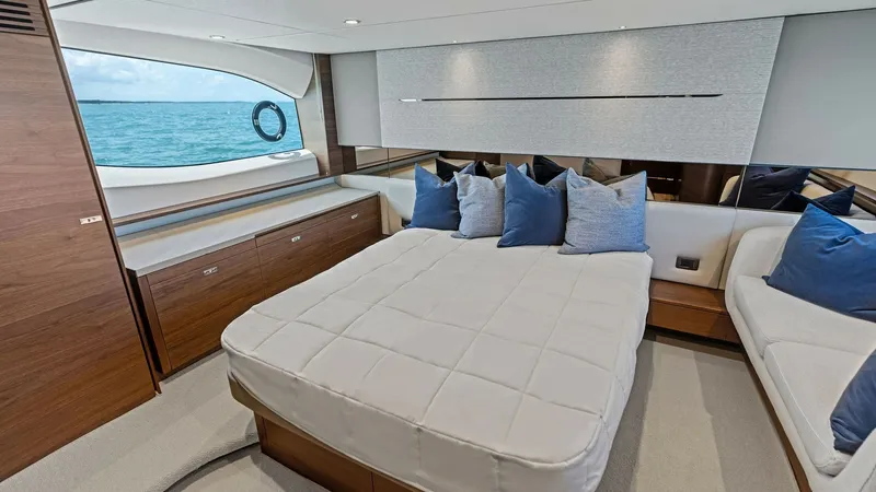 Slide: The Image of Luxurious Master Stateroom The master stateroom of the 2026 PRINCESS V55 offers a spacious and elegant retreat with a plush double bed adorned with stylish cushions. Natural light floods the room through large panoramic windows, highlighting the high-quality wood finishes and sleek - 6312348