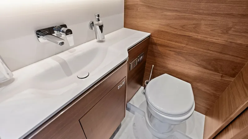 Slide: The Image of Luxurious Ensuite Bathroom This elegant ensuite bathroom on the 2026 PRINCESS V55 features sleek, modern fixtures, including a chic integrated sink and contemporary faucet. The high-gloss wood cabinetry offers ample storage, seamlessly blending with the minimalist design. Soft, amb - 6312352