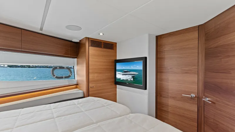 Slide: The Image of Luxurious VIP Stateroom Interior Experience the elegance of the 2026 PRINCESS V55's VIP Stateroom, featuring sleek wooden finishes and modern amenities. The cabin boasts a large window with scenic ocean views and a mounted flat-screen TV for entertainment. The spacious layout and sumptuo - 6312354