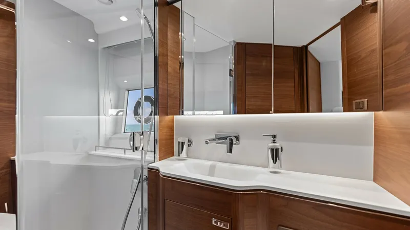 Slide: The Image of Elegant VIP Stateroom En-Suite Bathroom This luxurious Master Stateroom en-suite bathroom on the 2026 PRINCESS V55 features sleek, modern fixtures and rich wooden cabinetry, creating a warm and inviting atmosphere. The spacious layout includes a large mirror and ample lighting, enhancing the se - 6312357