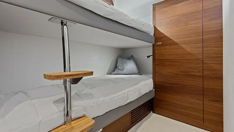 Slide: The Image of Guest Cabin with Bunk Beds The guest cabin of the 2026 PRINCESS V55 features sleek and modern bunk beds, maximizing space and comfort. Rich wooden finishes contrast beautifully with the soft, neutral bedding, creating a warm and inviting atmosphere. This well-designed space is perf - 6312358