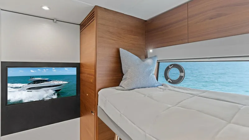 Slide: The Image of Guest Cabin with Bunk Bed This inviting guest cabin on the 2026 PRINCESS V55 features a sleek bunk bed setup, maximizing space and comfort. The warm wooden finishes and elegant design create a relaxing atmosphere, complemented by natural light streaming through the porthole. A wal - 6312360