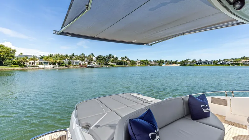 Slide: The Image of Spacious Cockpit Deck with Sunshade and Sun Lounger The 2026 Princess V55 features a luxurious aft deck with plush seating and a retractable sunshade. The expansive layout is perfect for entertaining, offering stunning views of the surrounding waters. High-quality finishes and comfortable cushions invite r - 6312361