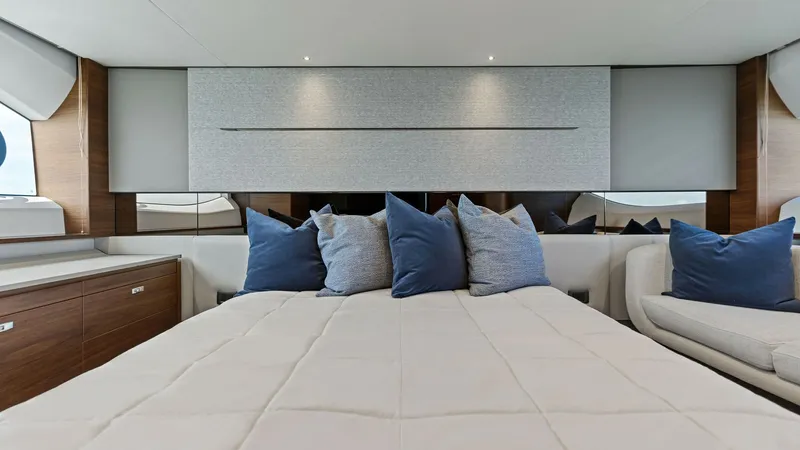 Slide: The Image of Luxurious Master Stateroom The master stateroom of the 2026 PRINCESS V55 exudes elegance with its plush bedding and contemporary design. Soft ambient lighting and sleek wood finishes create a serene atmosphere, complemented by the stylish blue and gray accent pillows. Spacious cabi - 6312326