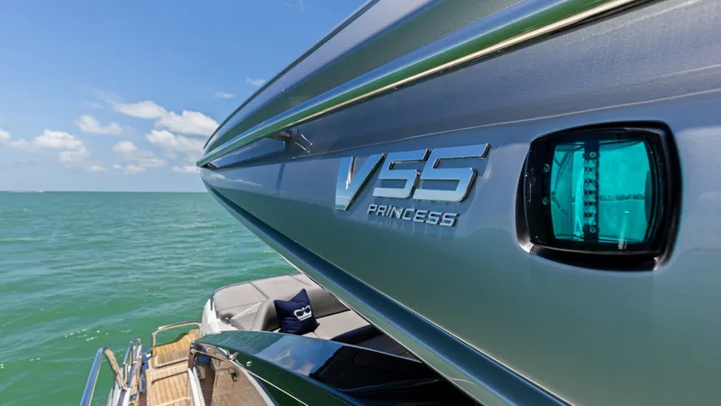 Slide: The Image of Sleek Exterior with Logo Detail The 2026 PRINCESS V55 showcases a sleek and modern exterior design, highlighted by its stylish chrome logo. The streamlined hull reflects the craftsmanship and elegance synonymous with Princess yachts. This angle also offers a glimpse of the spacious aft - 6312365