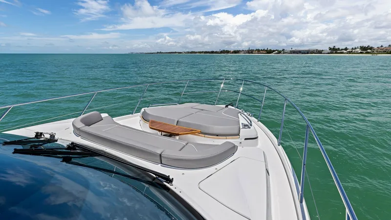 Slide: The Image of Bow Sunpad and Seating Area The 2026 Princess V55 features a luxurious bow with expansive sunpads, perfect for soaking up the sun. The sleek design is complemented by plush gray upholstery and a stylish wooden table, adding a touch of elegance. The wrap-around stainless steel railin - 6312367