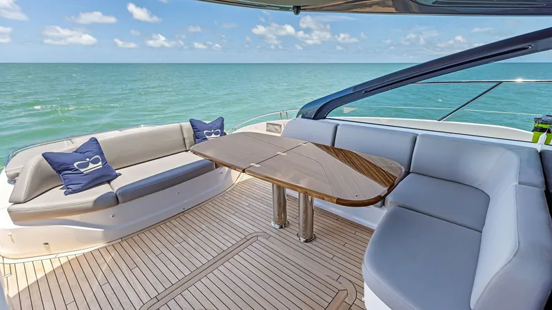 Slide: The Image of Spacious Cockpit Deck Seating Area The aft deck of the 2026 PRINCESS V55 features luxurious wrap-around seating with a sleek, polished wood table, perfect for alfresco dining or relaxing. The teak decking adds a touch of elegance and durability, while the expansive view of the ocean enhanc - 6312327