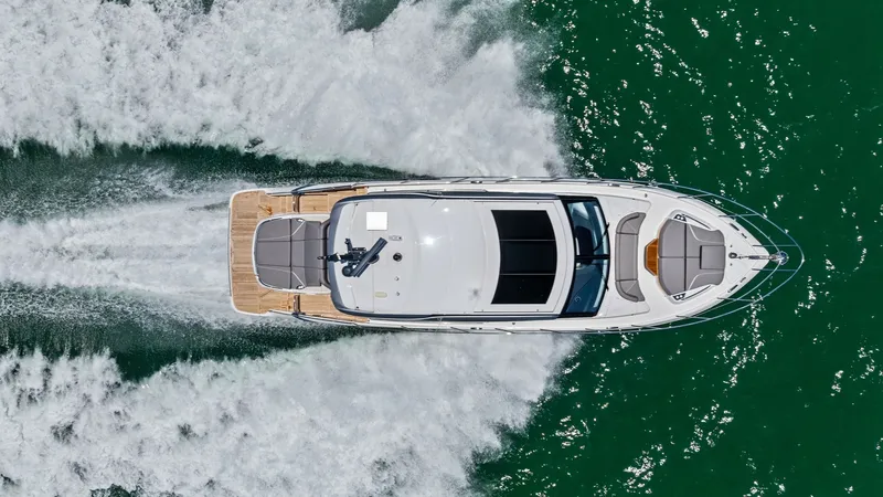 Slide: The Image of Aerial View of Princess V55 This striking aerial shot captures the sleek design of the 2026 Princess V55 as it glides through the water. The spacious aft deck features elegant seating, perfect for relaxation or entertaining. The yacht's streamlined profile and modern finishes highli - 6312378