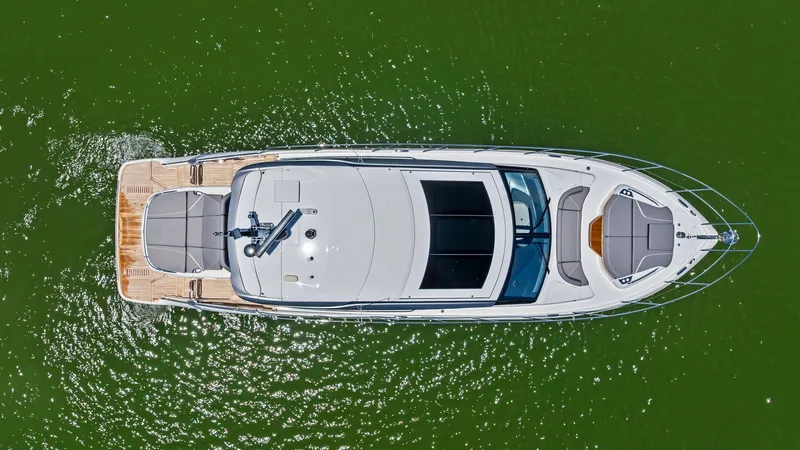Slide: The Image of Aerial View of 2026 Princess V55 This aerial shot of the 2026 Princess V55 showcases its sleek, modern design and spacious layout. The expansive sunbathing area at the bow and the elegant teak decking at the stern highlight the yacht's luxurious features. Large windows in the superstruct - 6312329