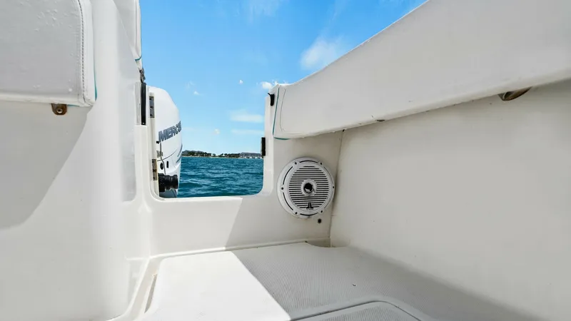 Slide: The Image of Cockpit with Speaker and Engine View This image showcases the clean and spacious cockpit area of the 2015 SeaVee 320Z. The white deck surfaces are complemented by a built-in marine speaker for enhanced audio experiences. In the background, the powerful Mercury outboard engine is visible, emp - 6312144